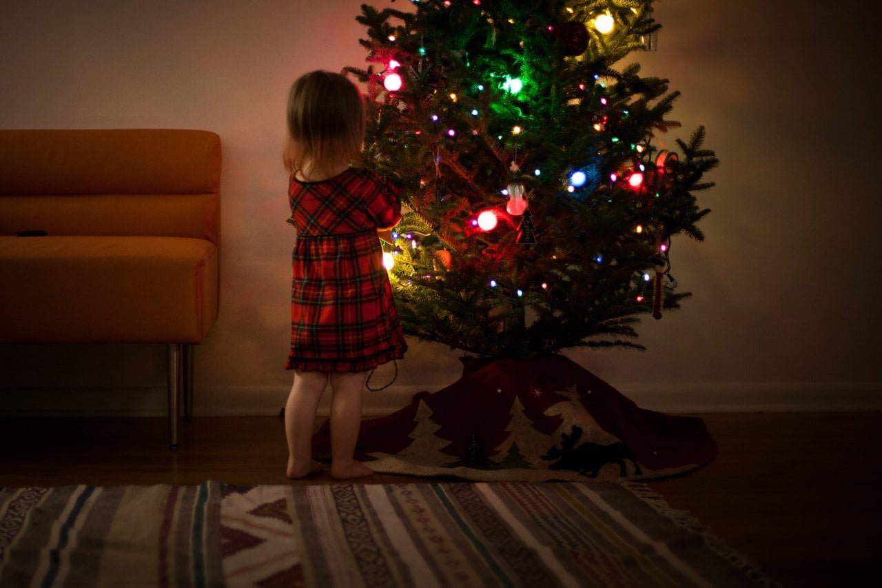 Girl on a carpet decorating a christmas tree